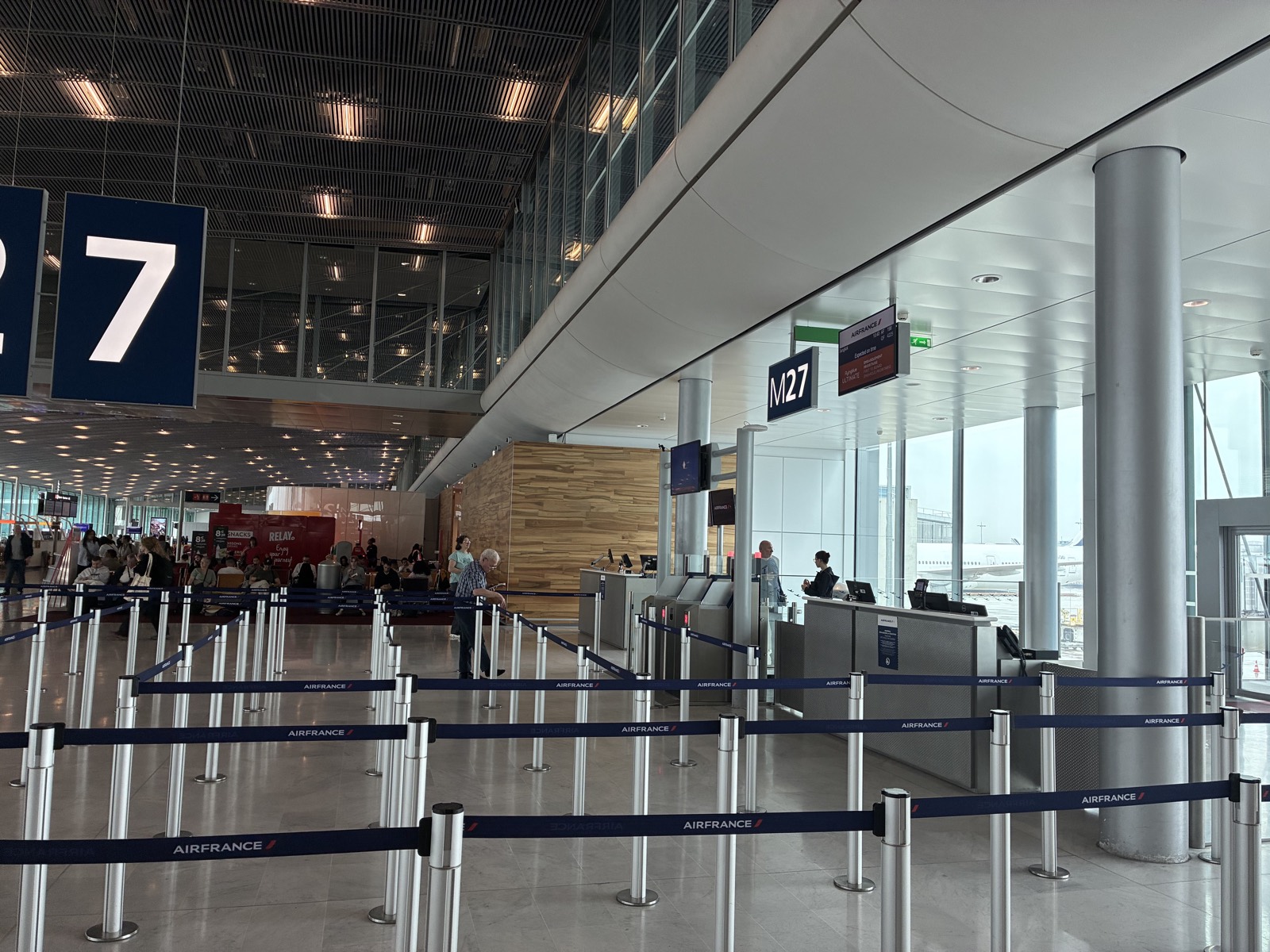 File d'embarquement vide devant la porte M27, sangles Air France tendues entre les poteaux