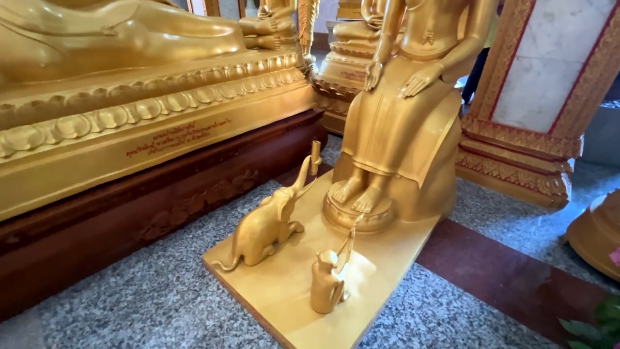 Au pied d'un bouddha doré, un éléphant et un singe sculptés lui tendent une offrande