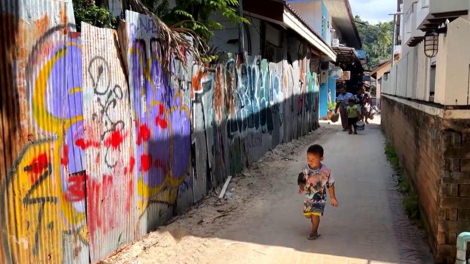 Un enfant joue devant les tôles couvertes de graffitis