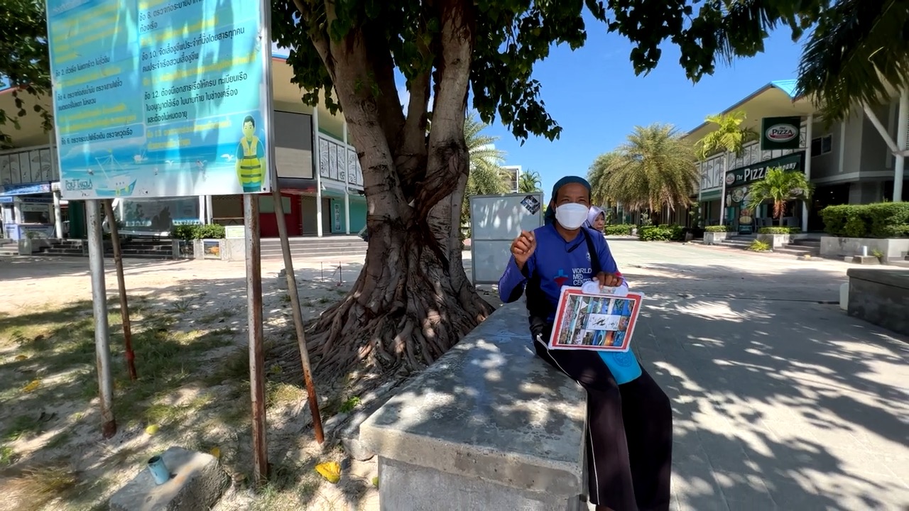 Manou, ses affichettes à la main, dans la rue du village