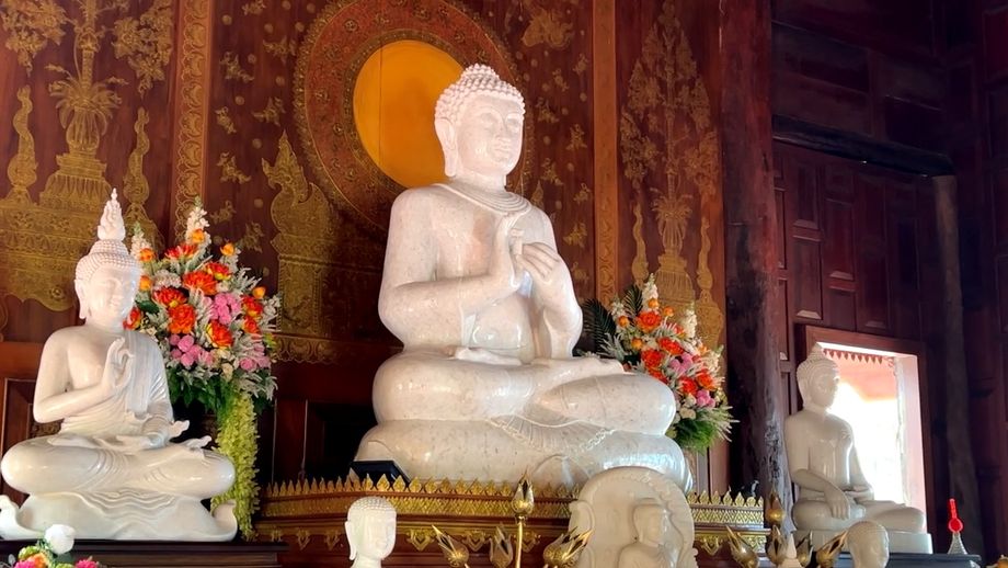 Le Bouddha de marbre blanc, entouré de fleurs