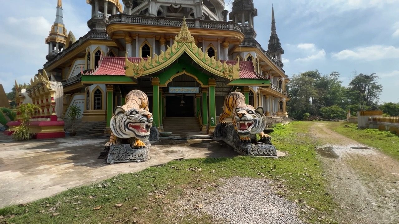 Un temple aux façades vertes et rouges, deux statues de tigres de part et d'autre de l'entrée