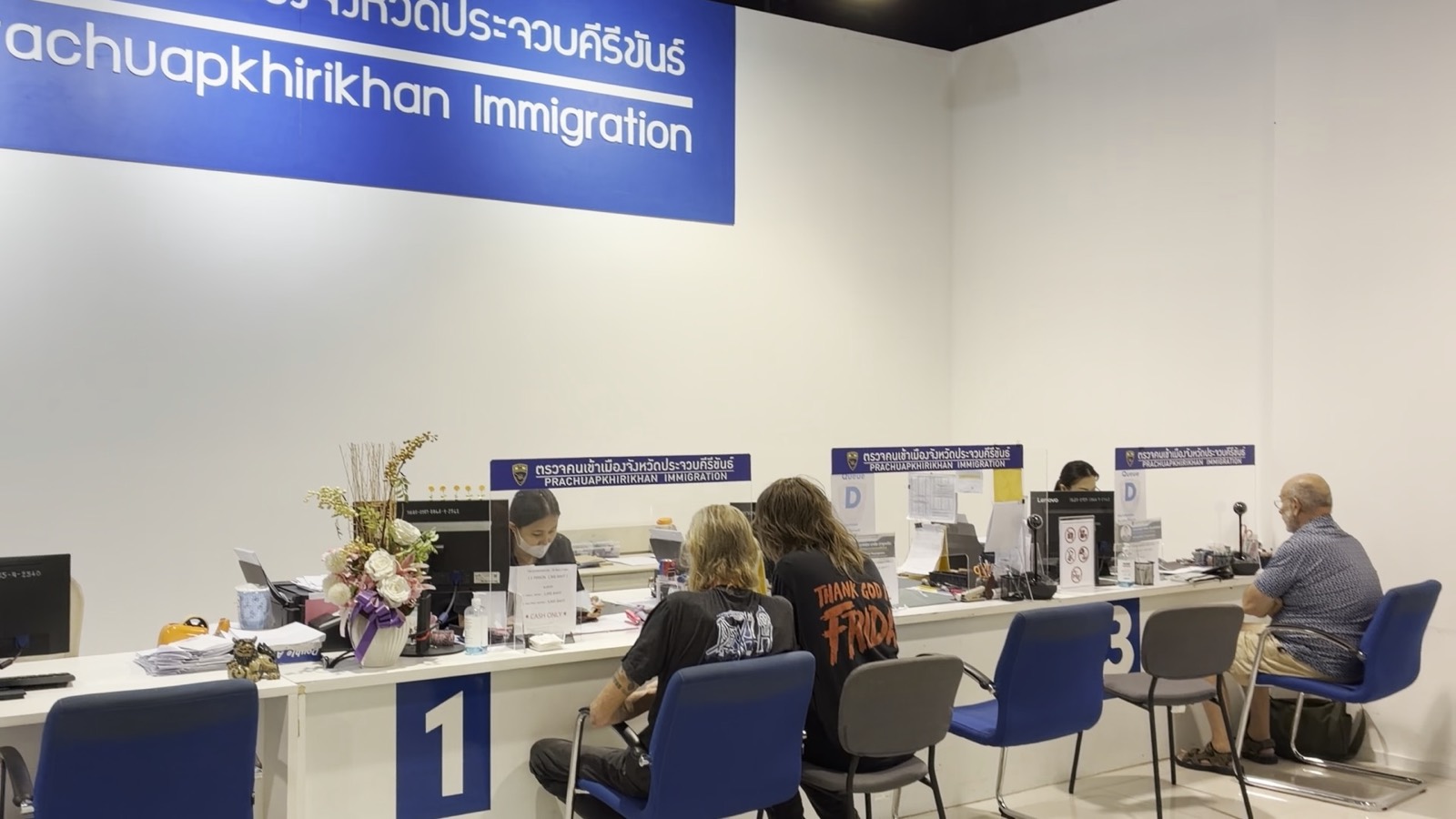 Trois guichets du bureau de l'immigration de Prachuap Khiri Khan, des étrangers assis face aux agents